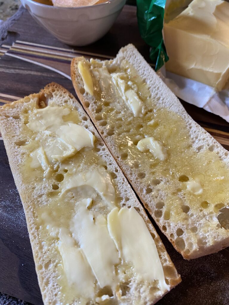 An open baguette with melting butter spread over it