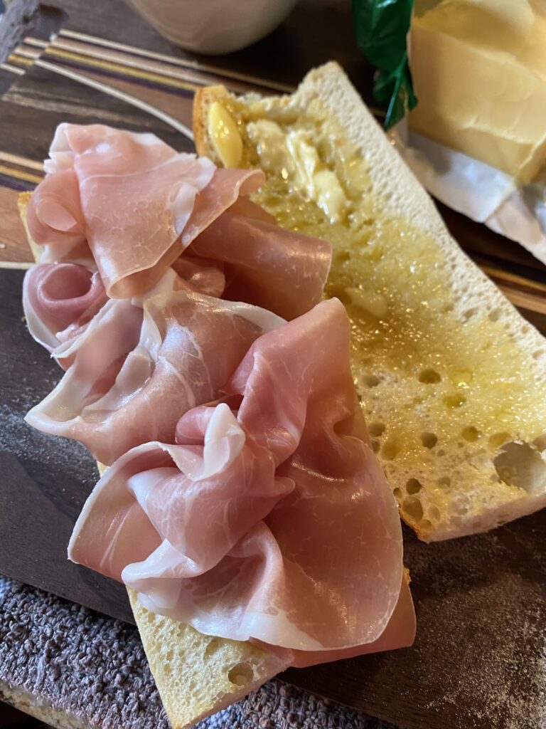 An open baguette sandwich with prosciutto