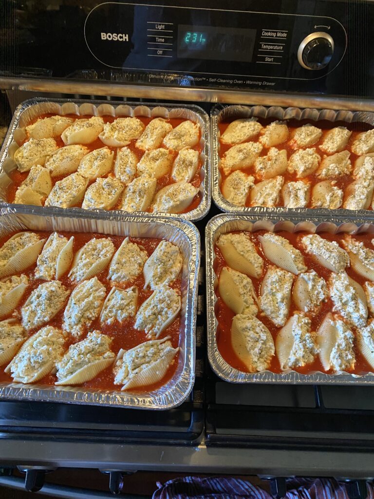 Four tins of stuffed shells in sauce on top of the stove