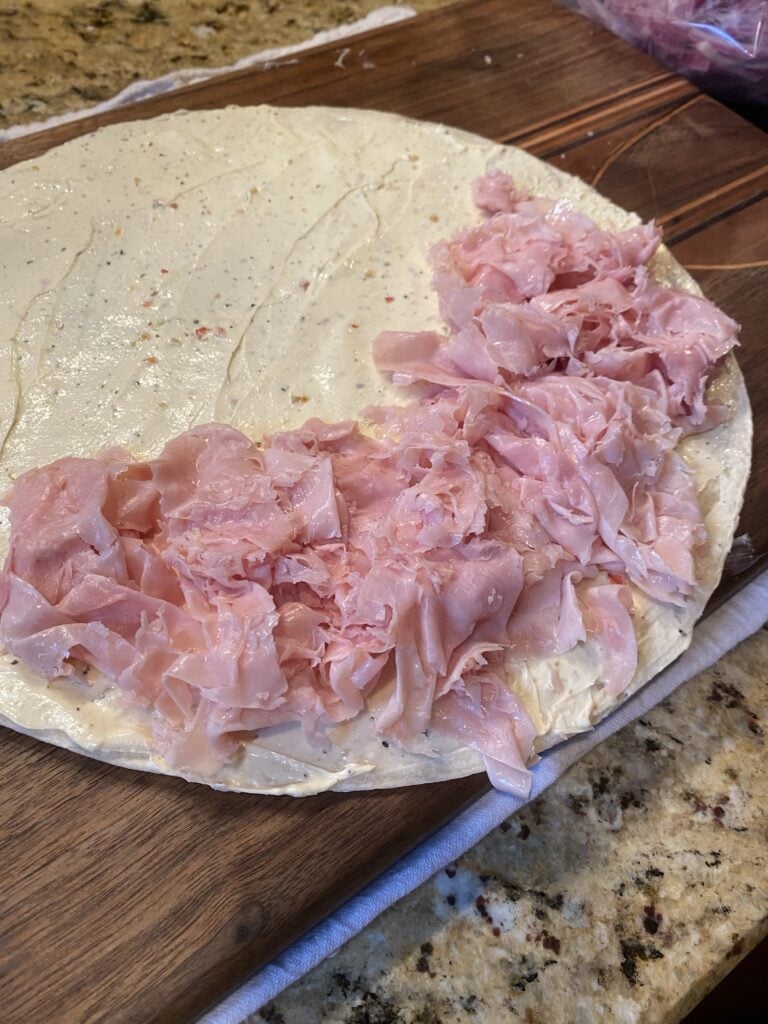 Deli meat on a tortilla with sandwich spread on it