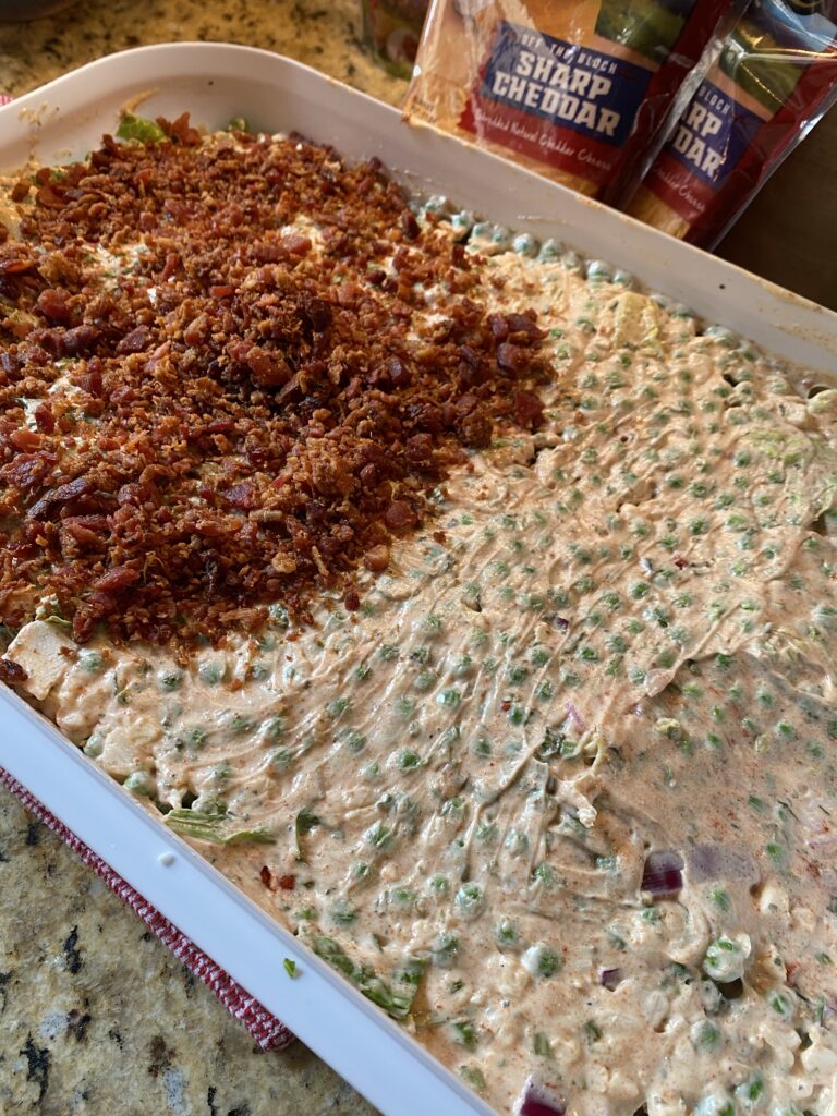 The salad half covered with bacon, showing the dressing underneath