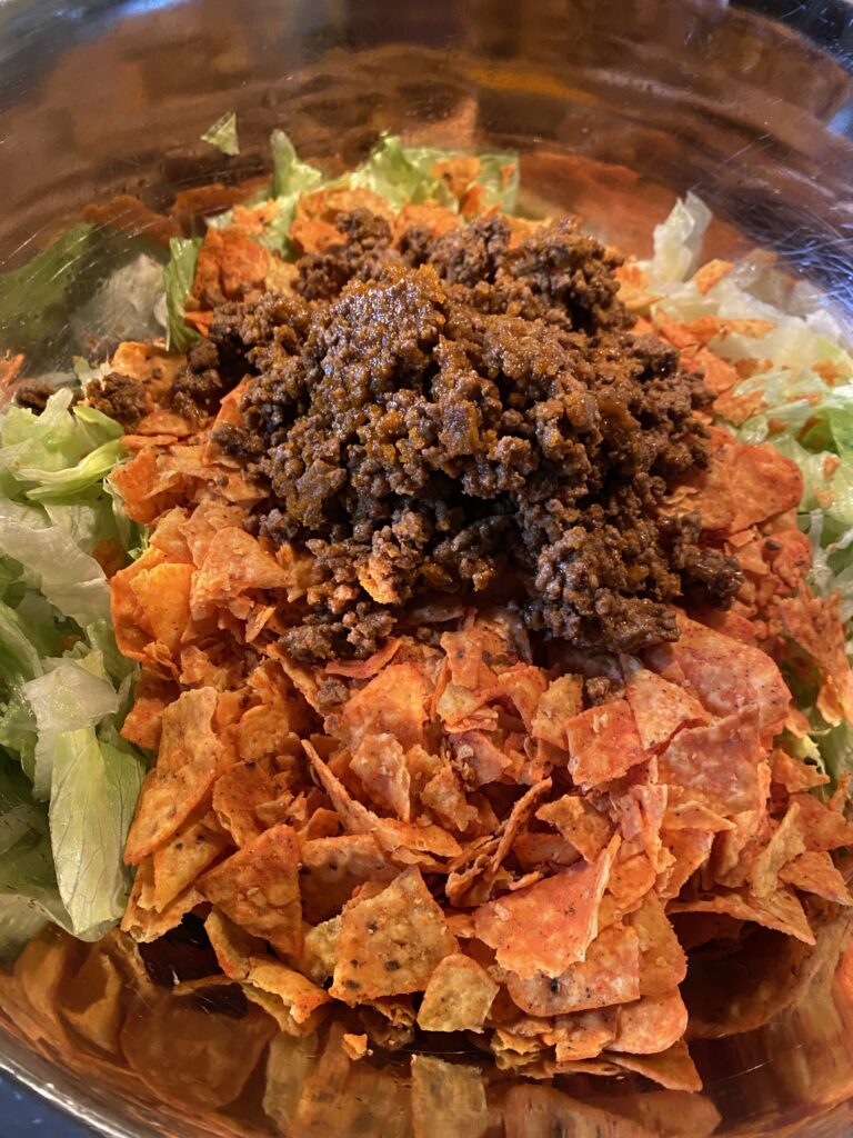 Lettuce topped with crunched up Doritos and ground beef