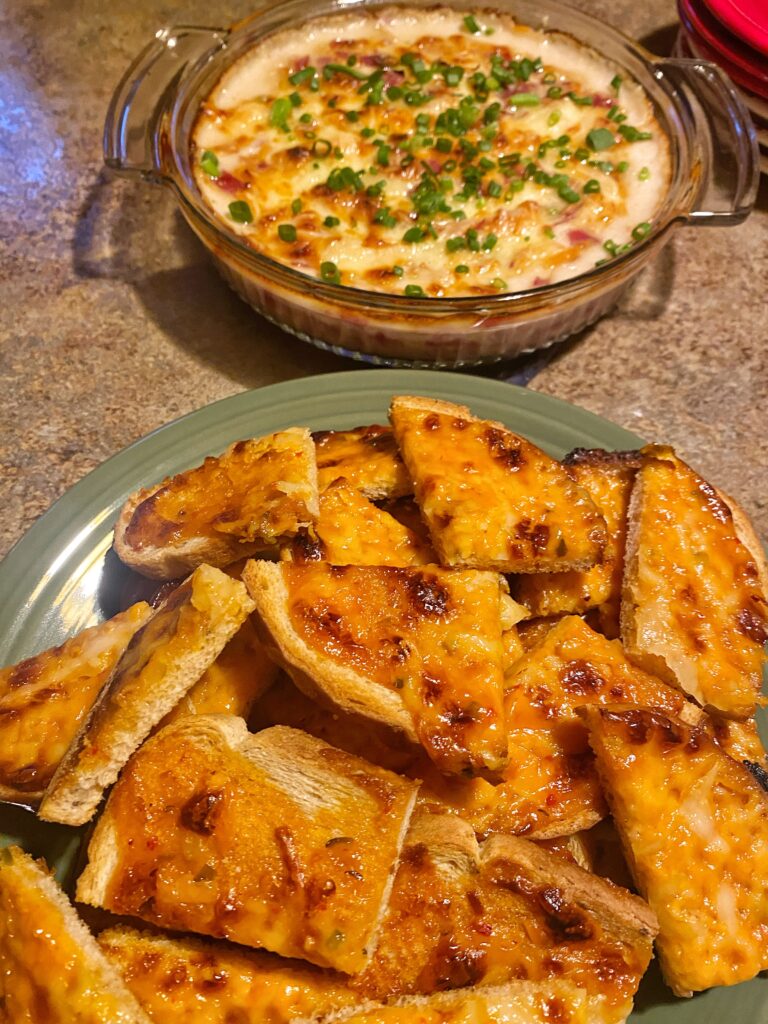 Toasty cheese points on a plate in front of baked reuben dip