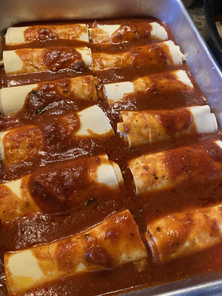 A close up of the rolled manicotti in a baking dish