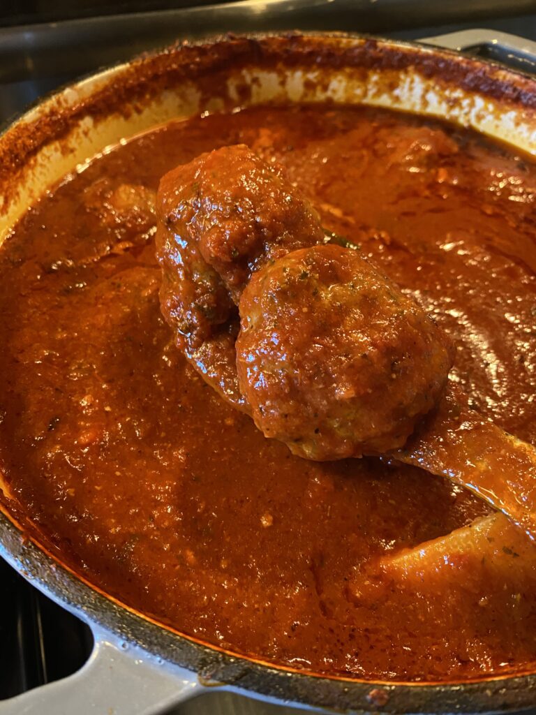 A ladle of meatballs over Sunday sauce