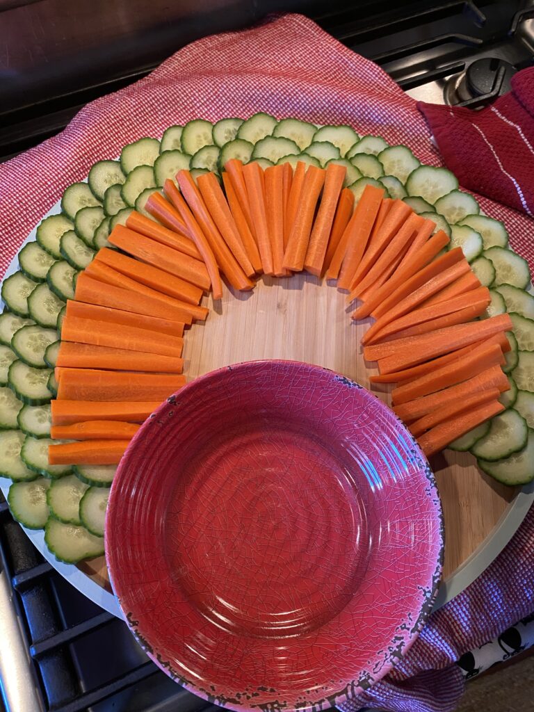 A red bowl with sliced carrots and cucumbers