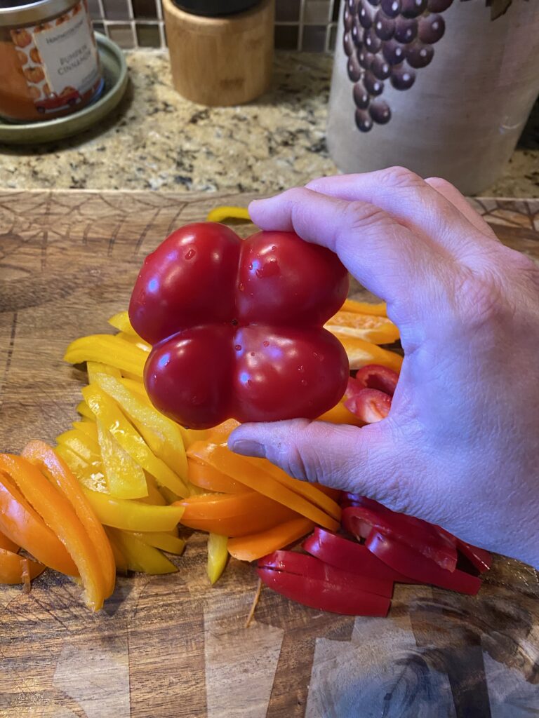 A red bell pepper over sliced bell peppers of other colors