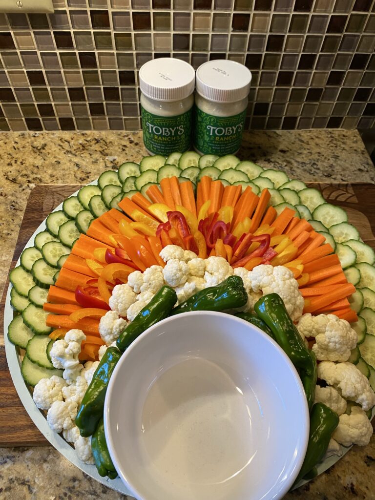 A white bowl surrounded by various veggies arranged into the body of a turkey