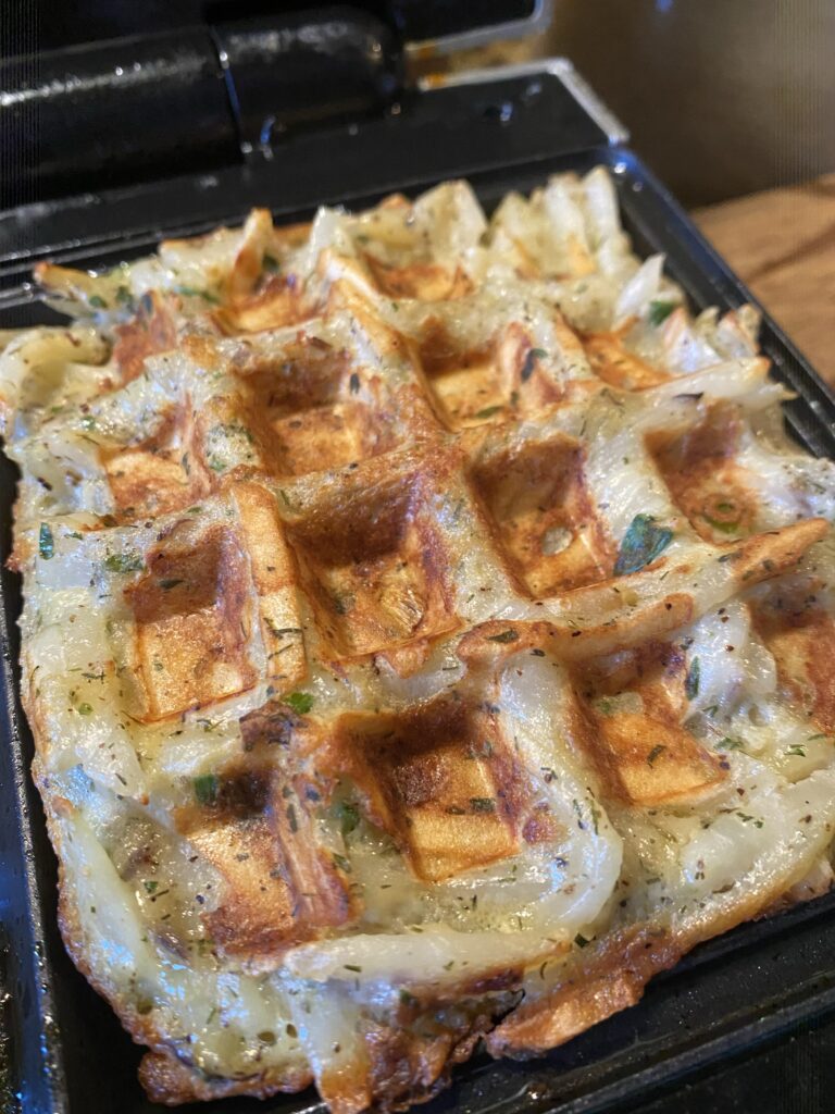 A potato waffle in a waffle iron