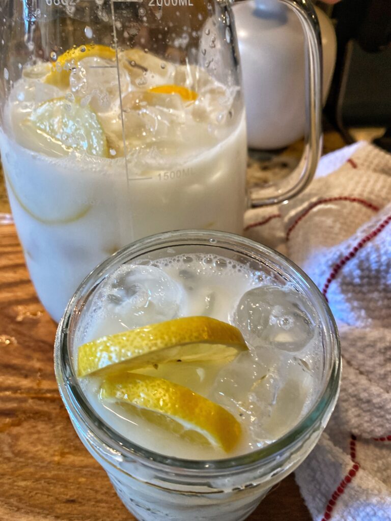 A glass of creamy white lemonade with lemon slices, seen from above