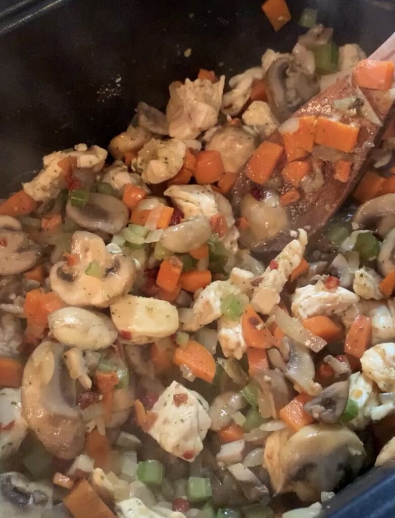 A close up of chicken, carrots, onions, and mushrooms