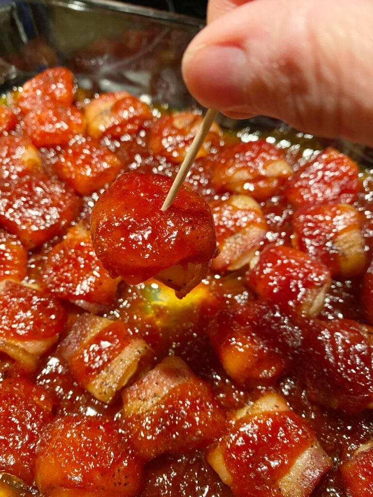 A bacon wrapped water chestnut with BBQ sauce on a toothpick
