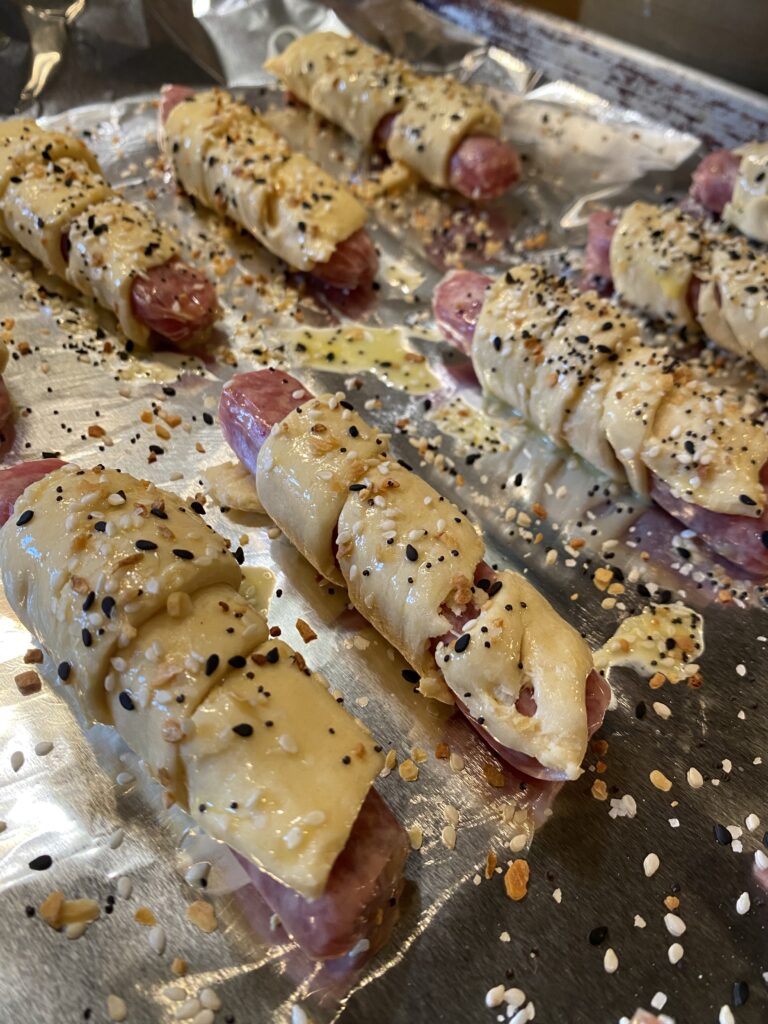 Biscuit dough wrapped around hot dogs and topped with everything bagel seasoning
