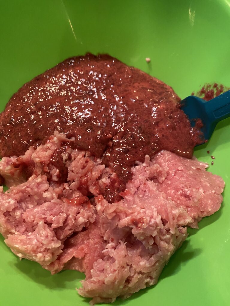 Blended liver and ground pork being mixed together with a blue spatula