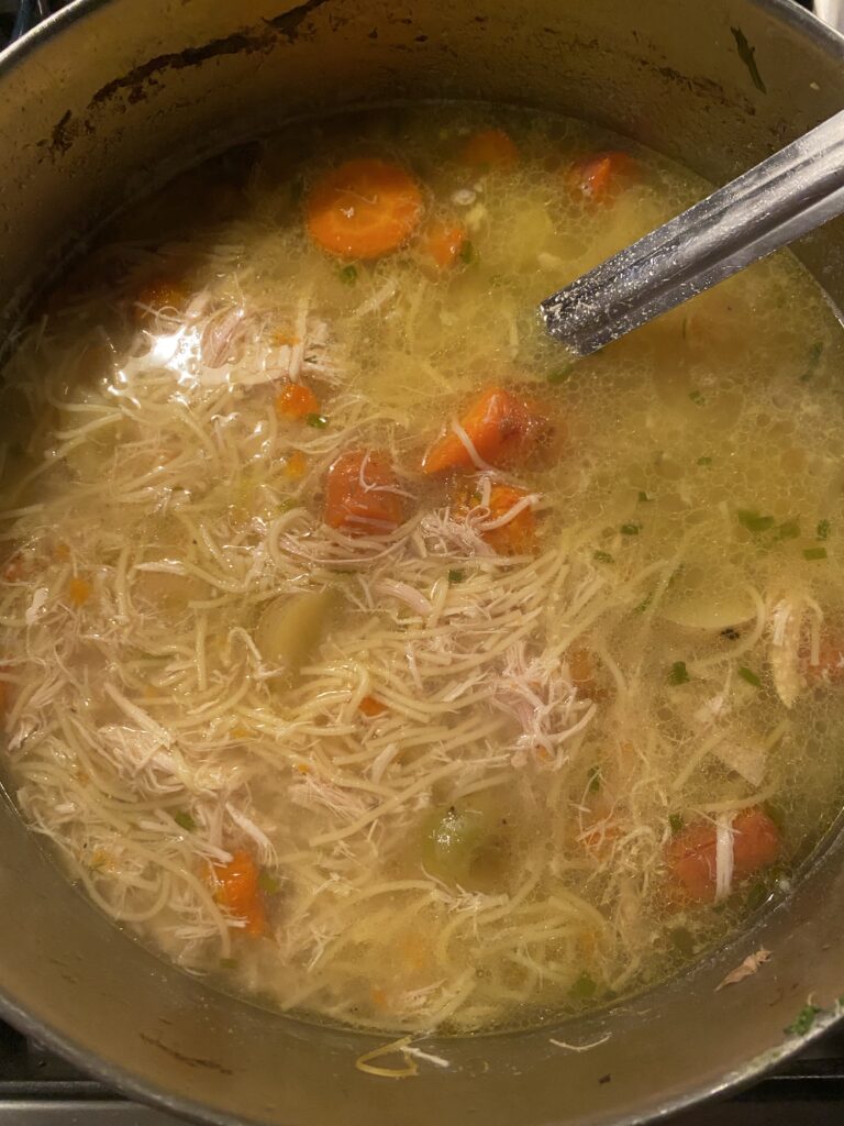 Chicken noodle soup in a pot with a ladle