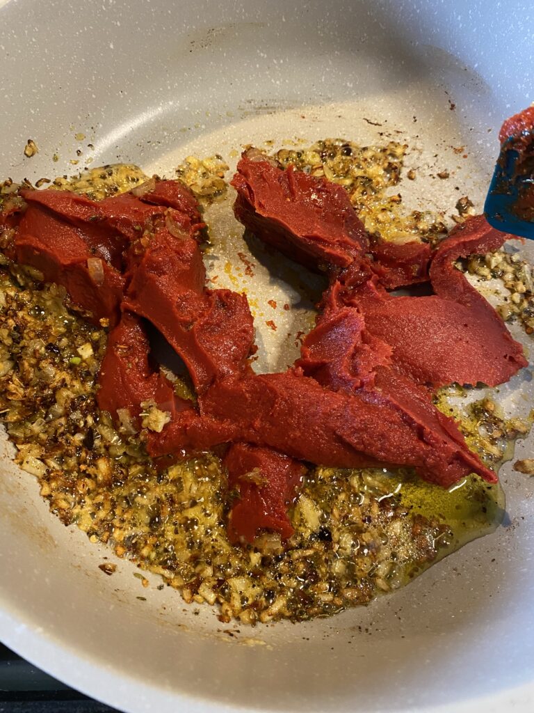 Tomato paste and oil and seasonings cooking in a pot