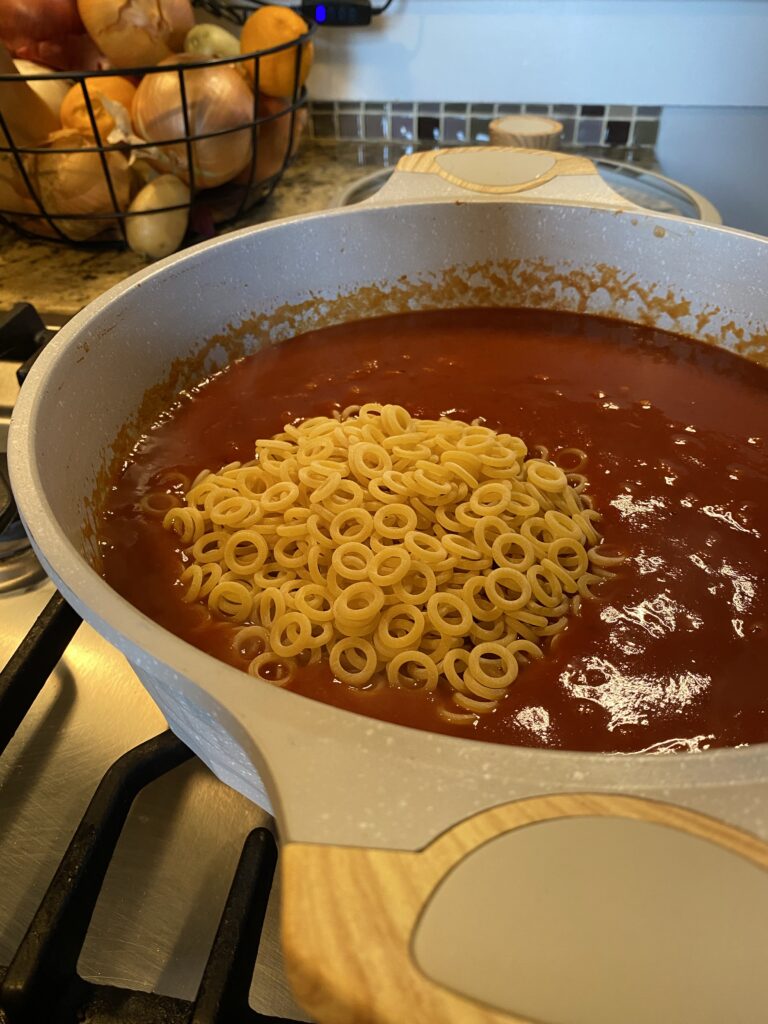 Ring pasta in a pot of tomato sauce