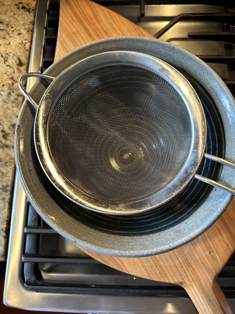A strainer over a blue bowl