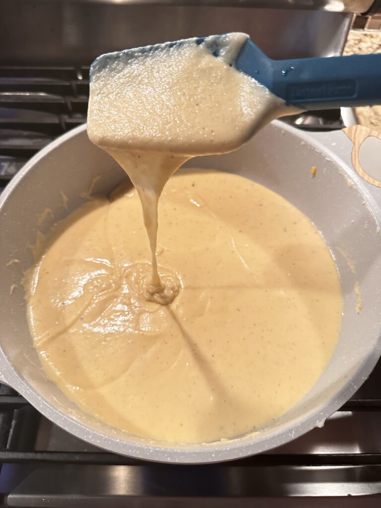 Cheese sauce being ladled out of a pot