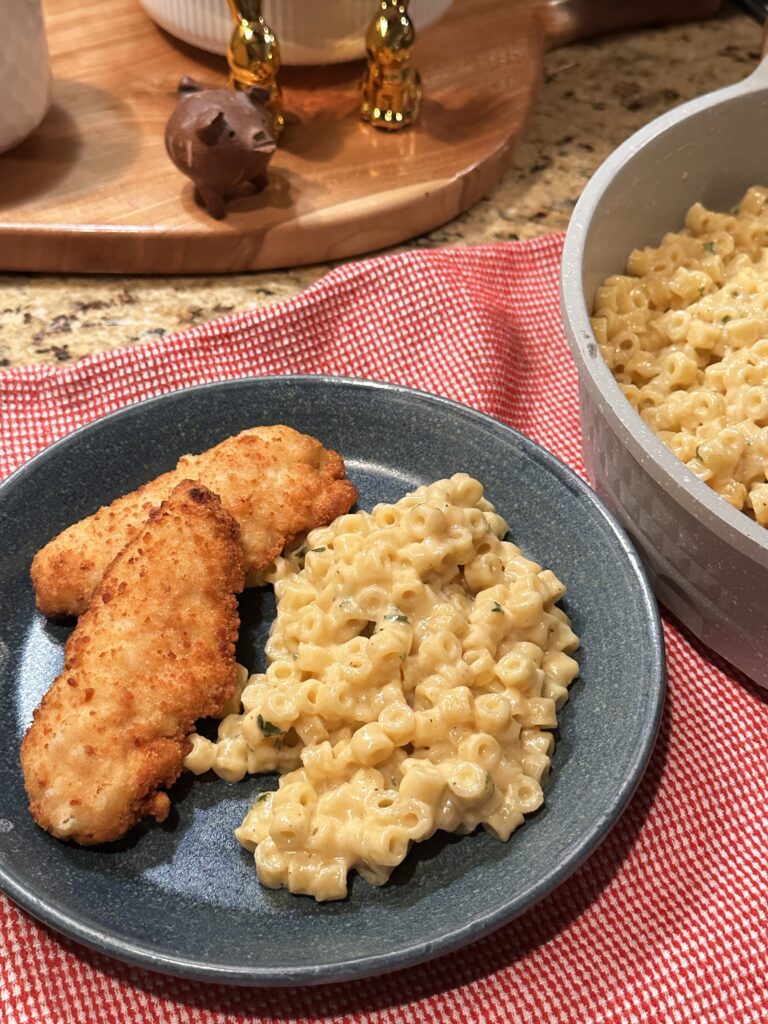 Chicken tenders and mini mac and cheese on a blue plate