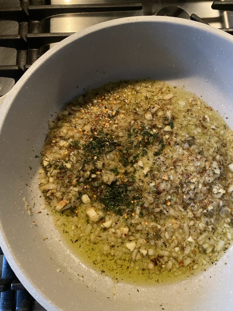 Onions, garlic, oil, and seasonings sizzling in a pan