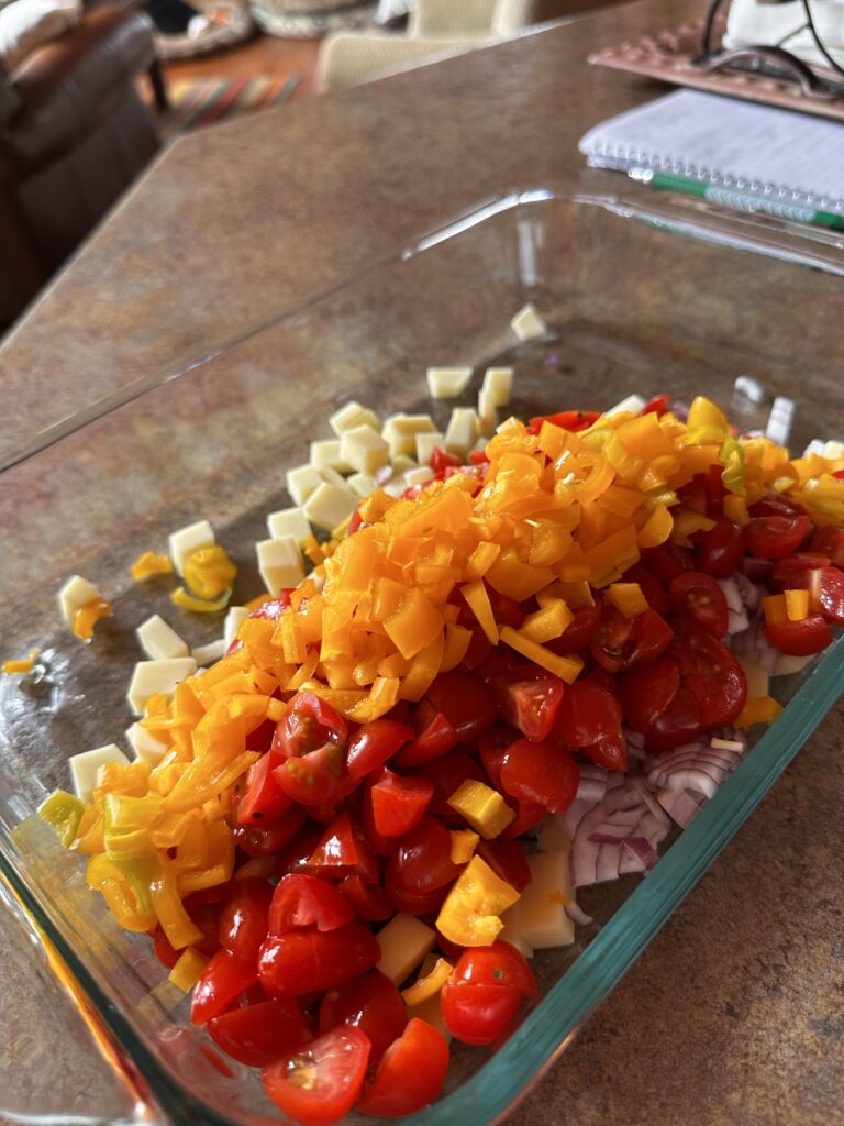 Chopped peppers and tomatoes and onions in a glass dish