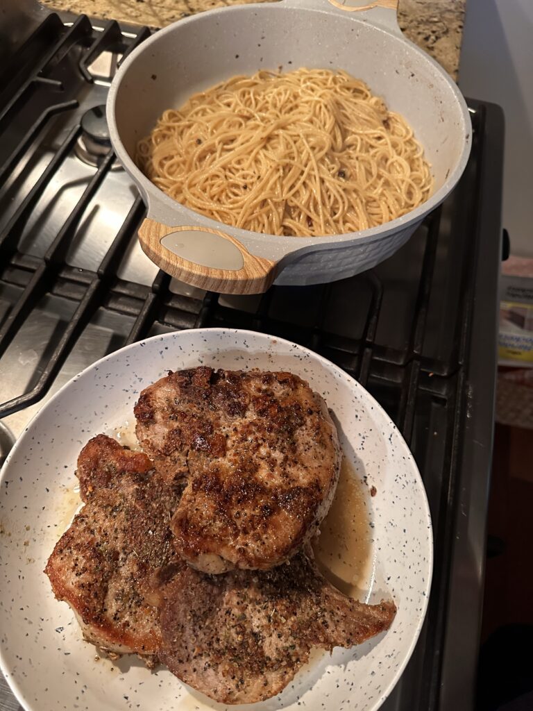 A pot of spaghetti next to a plate of pork chops