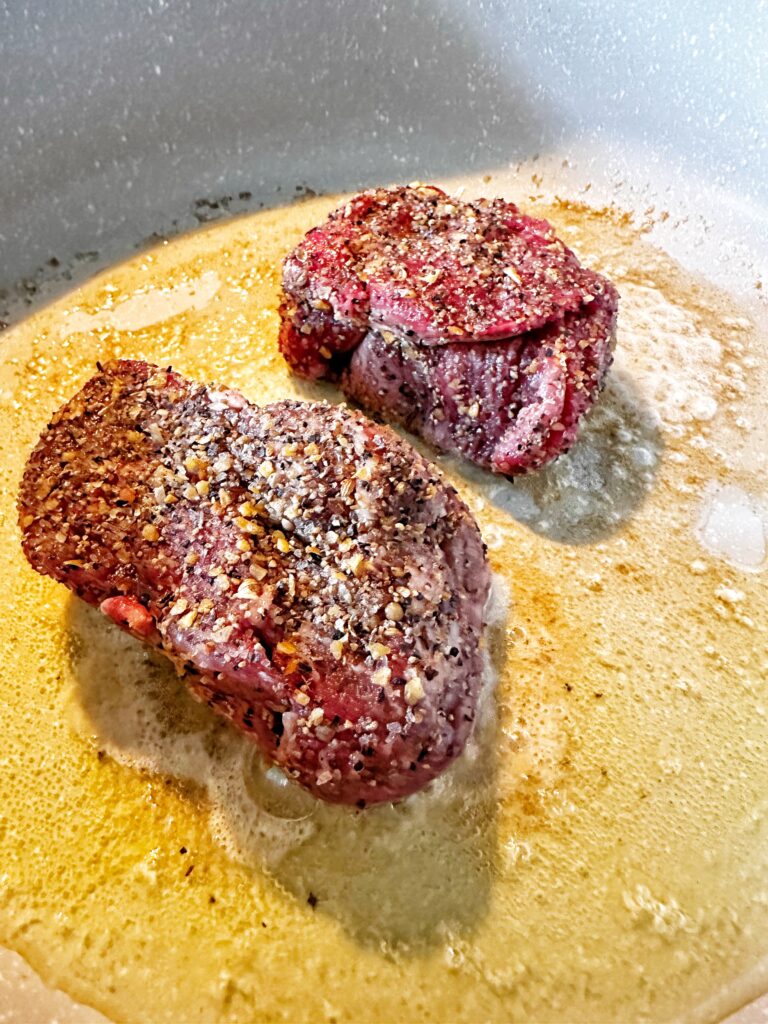 Seasoned steaks cooking in a pan
