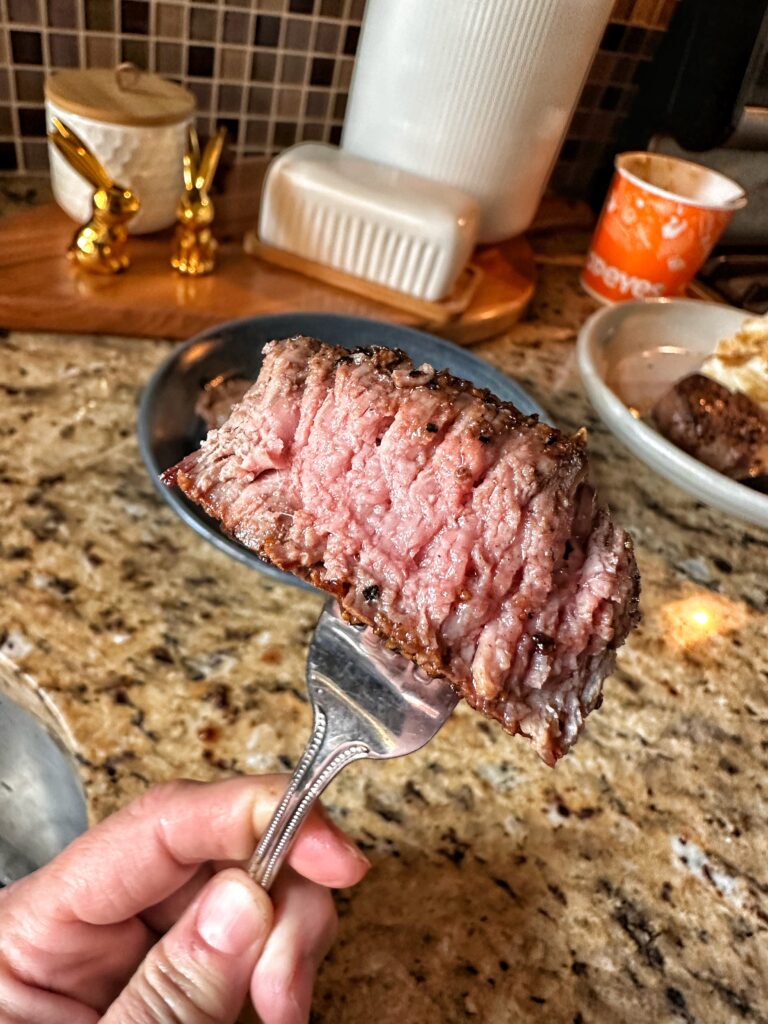 A medium rare piece of steak on a fork