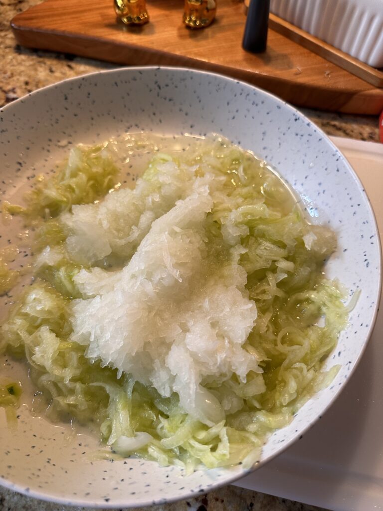 Grated cucumber and onion in a white bowl