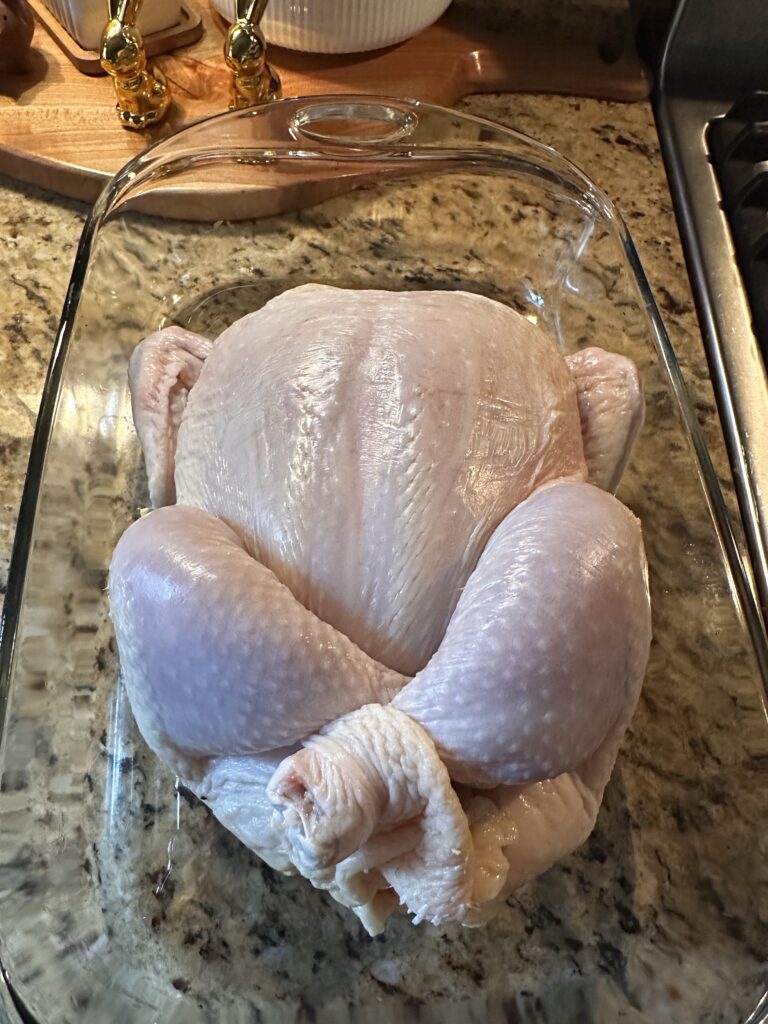 A whole, raw chicken in a glass baking dish