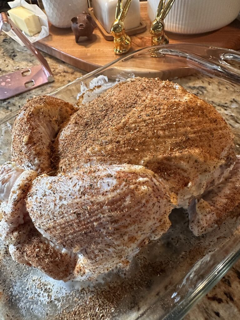 Seasoned whole raw chicken in a glass baking dish