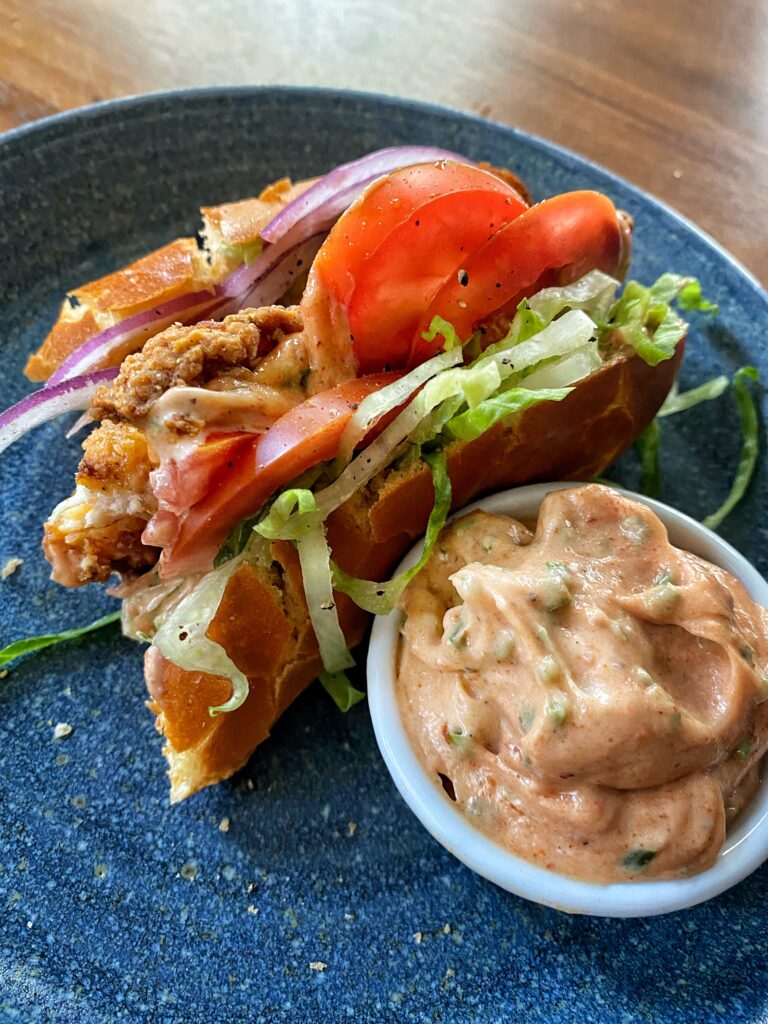 A half eaten bird dog sandwich next to dipping sauce