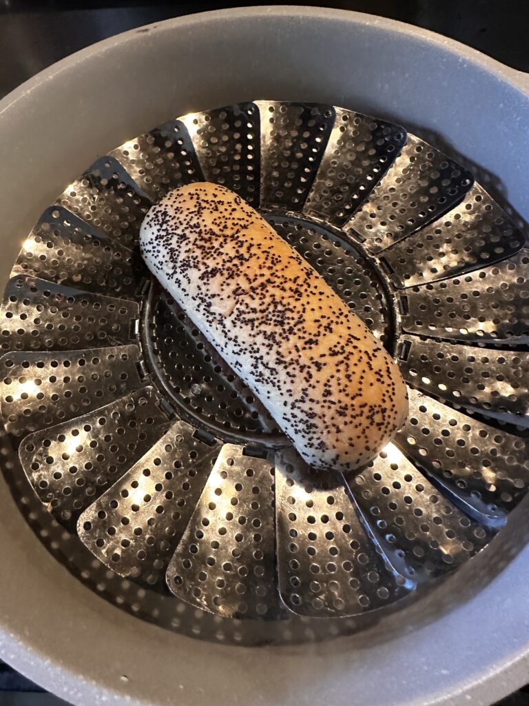 A poppy seed bun on a steamer plate