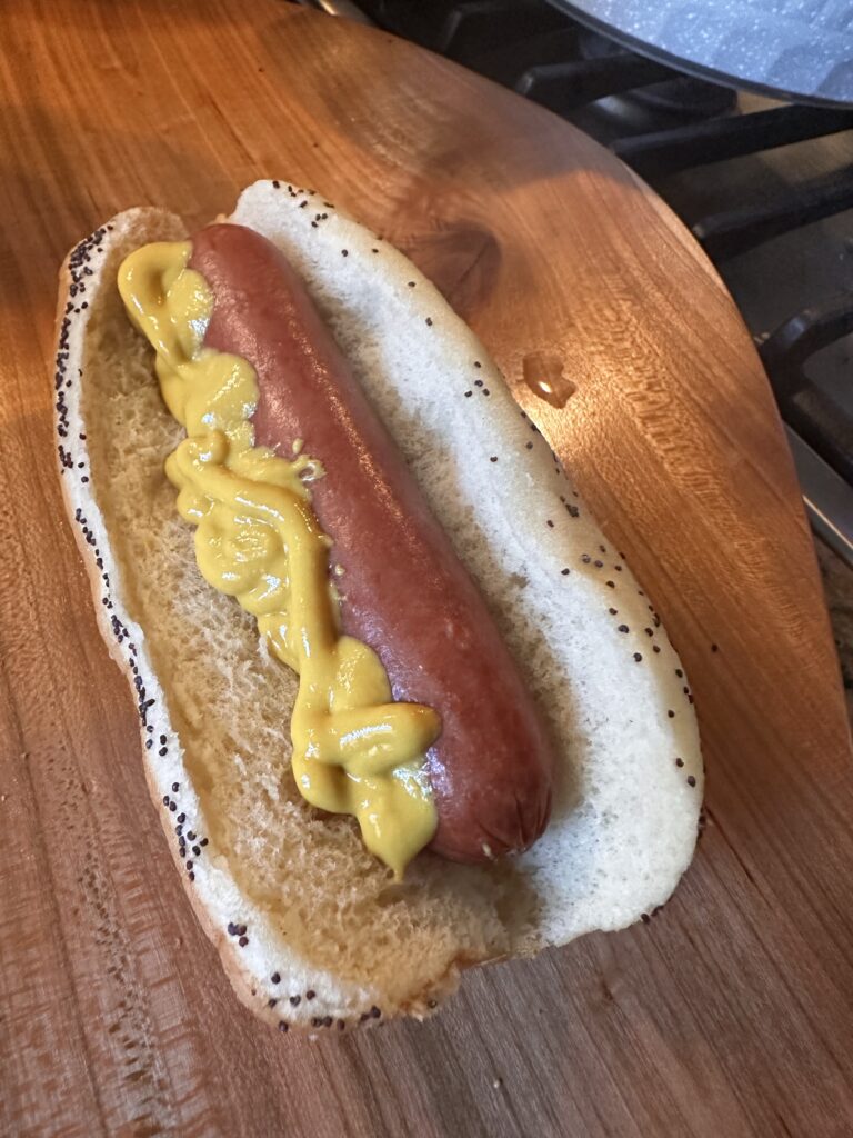 A hot dog on a poppy bun with mustard
