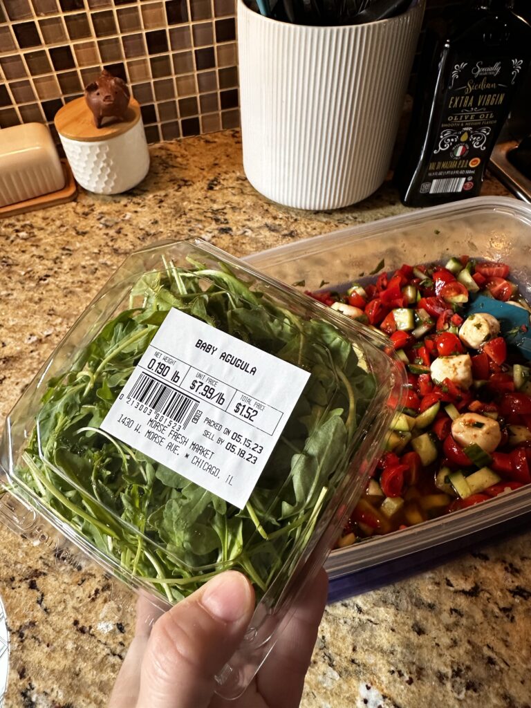 A container of baby arugula though there seems to be a typo as the label reads "agugula"