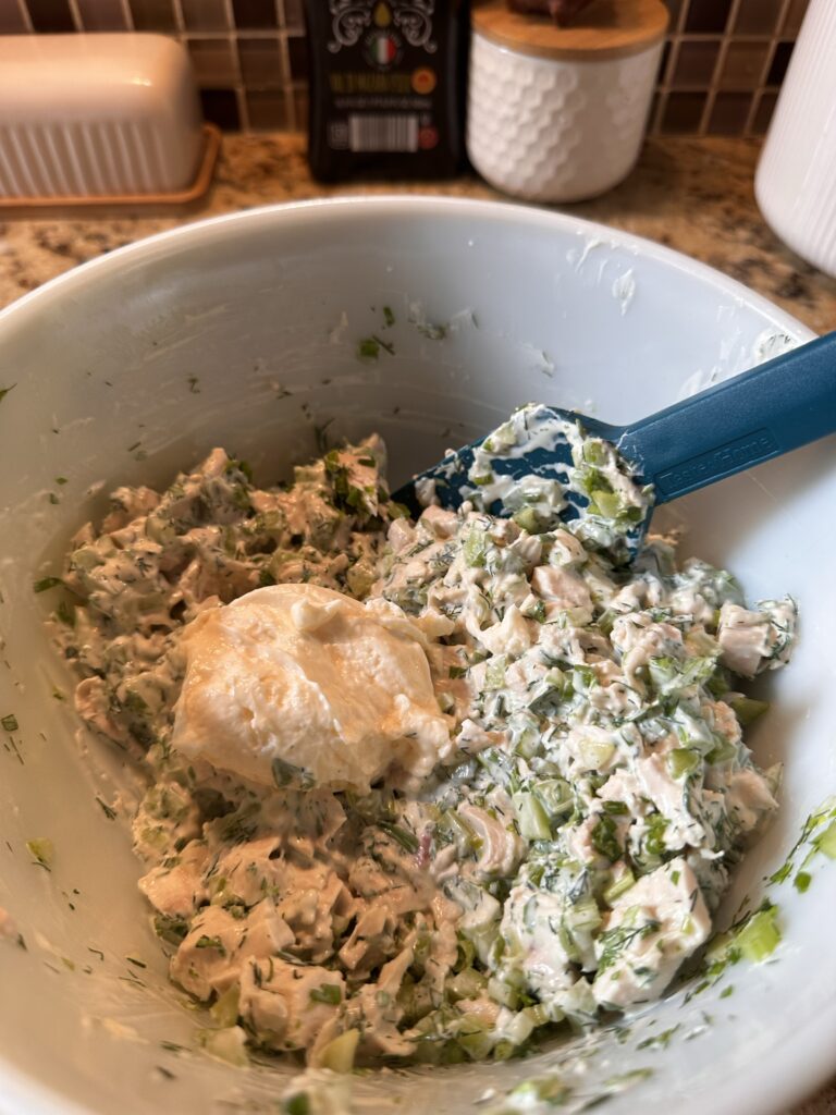 Mayo being mixed into the chicken salad