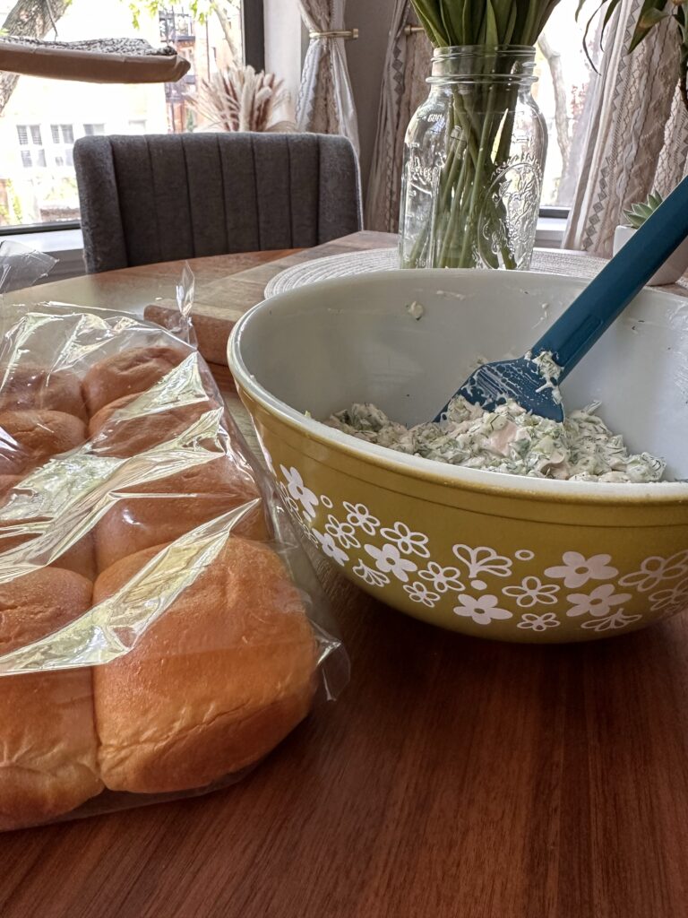 A bowl of chicken salad next to aq package of rolls