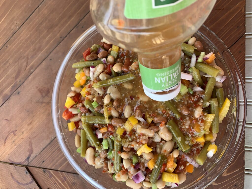 Zesty Italian dressing being poured on to the zesty bean salad