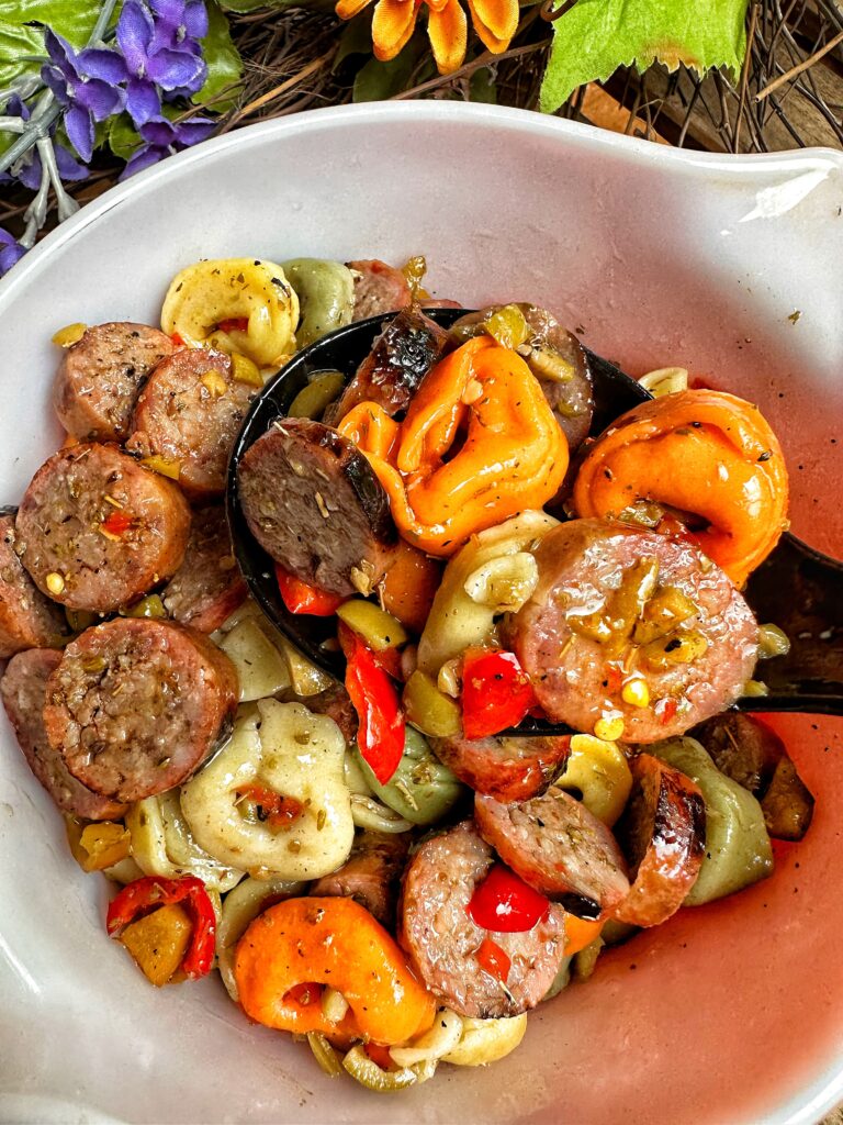 A serving spoon of sausage and tortellini salad