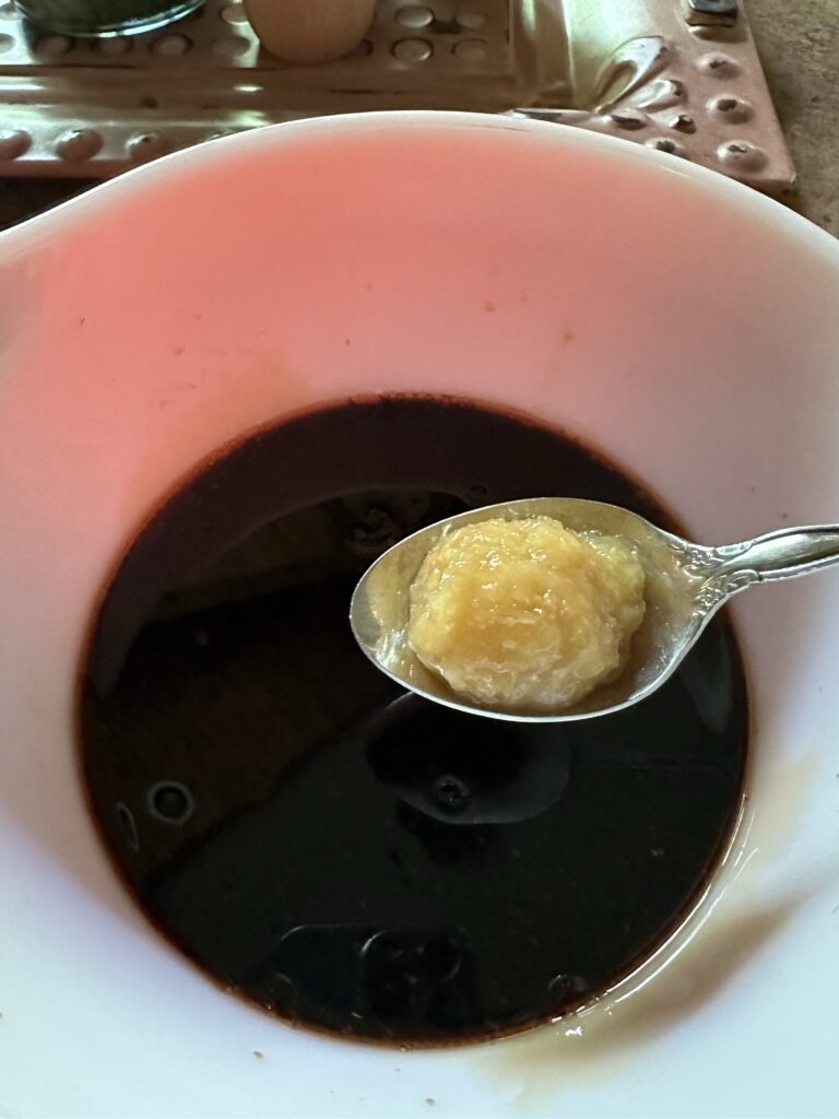 A spoon of grated ginger held over the marinade
