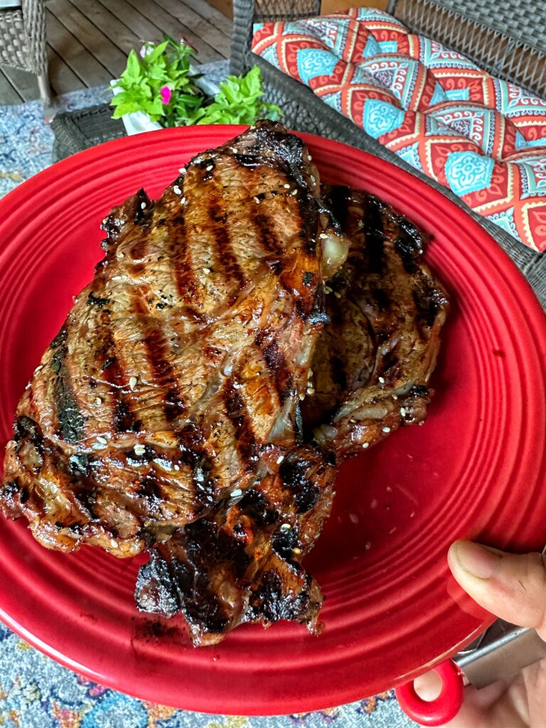 Two pieces of grilled steak on a red plate