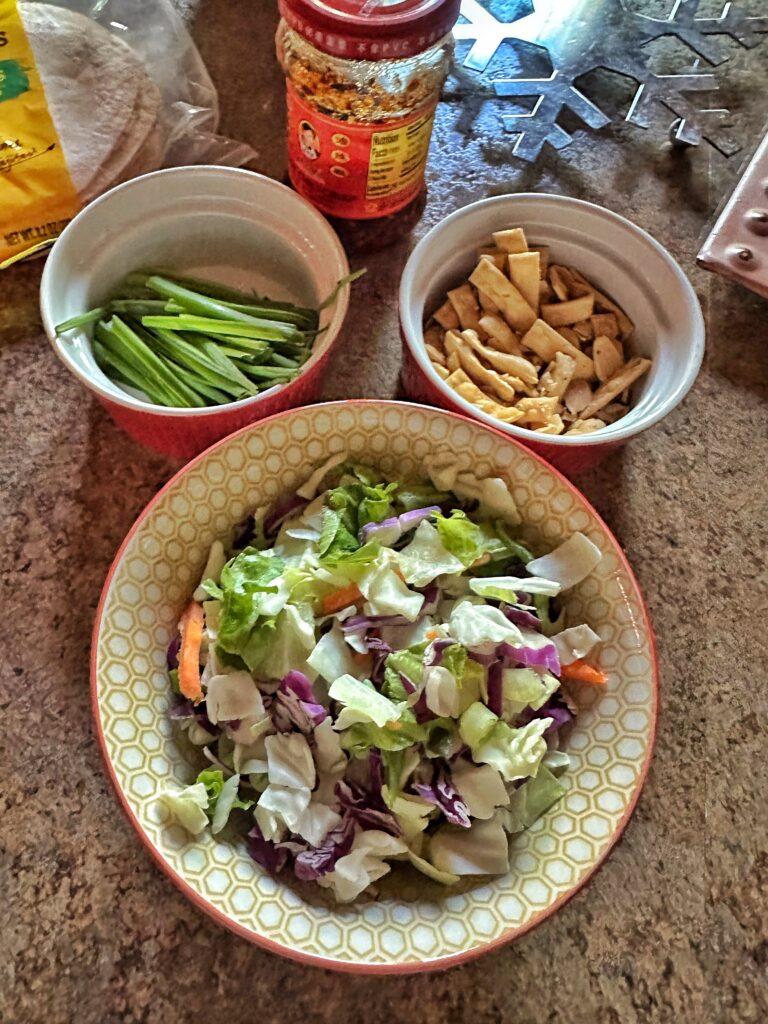 The toppings for the Korean beef tacos including green onions, Asian salad, and crispy wonton noodles