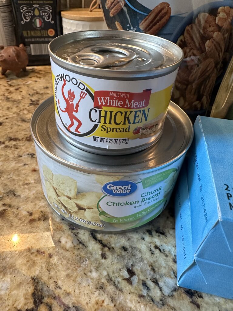 A can of chicken spread on top of a can of chicken breast chunks