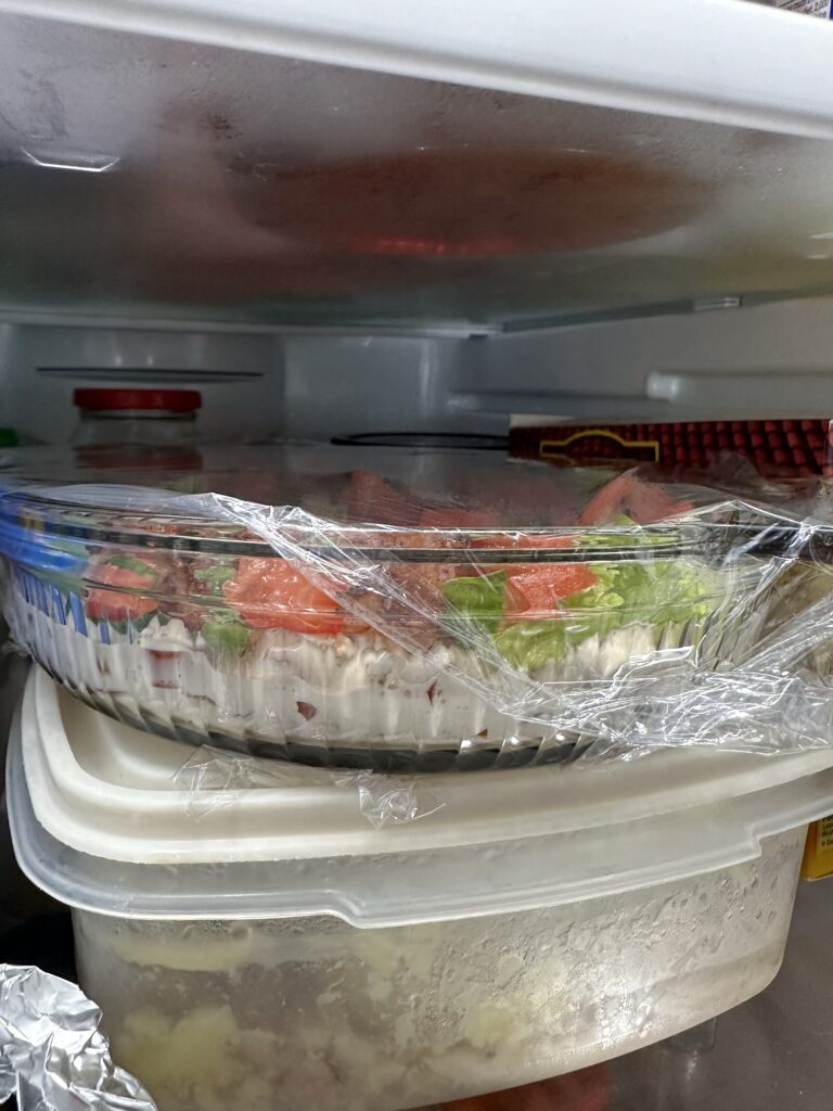 A glass dish of BLT dip seen from the side