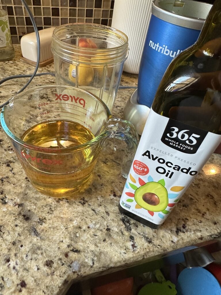 Avocado oil in a measuring cup next to the bottle