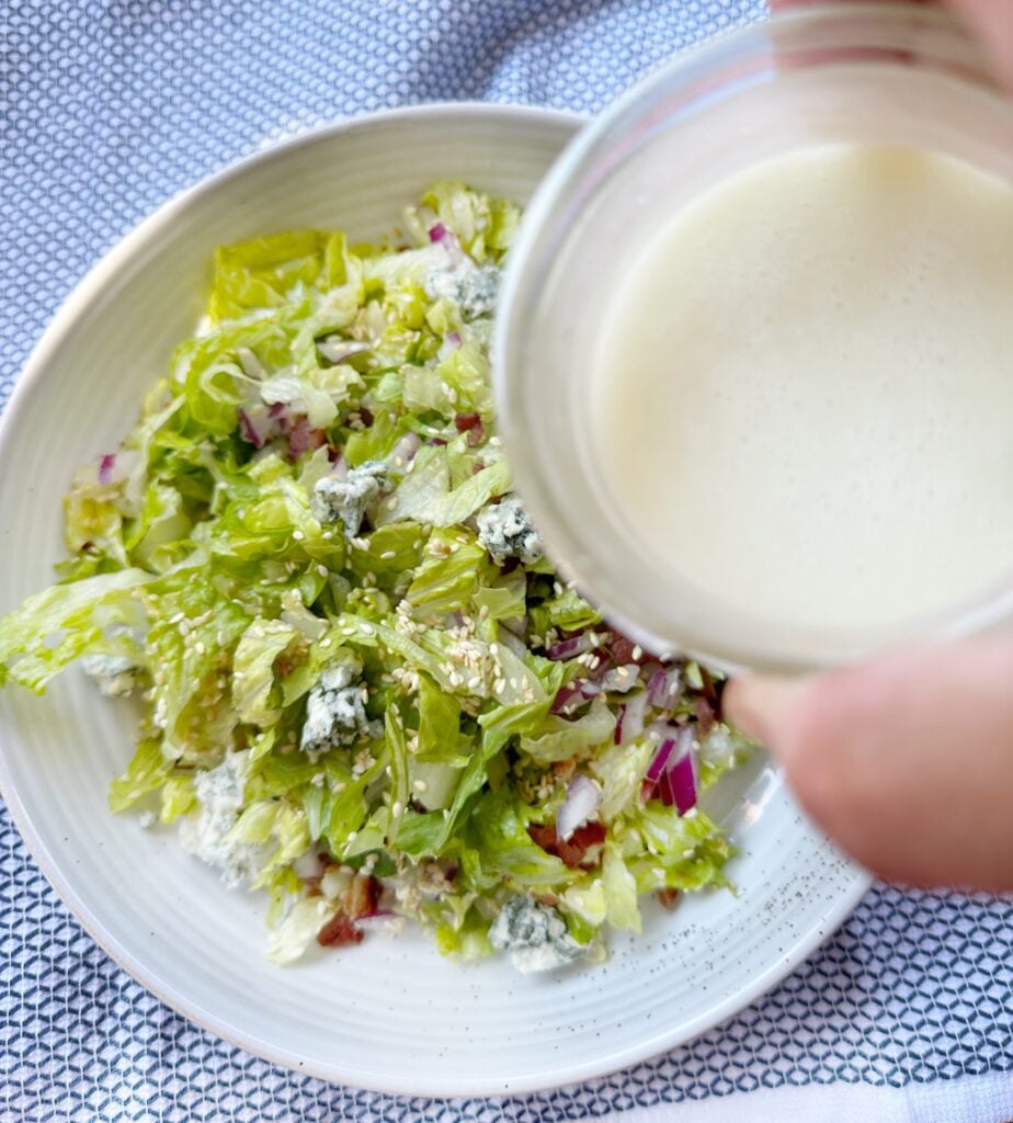 White dressing about to be poured over the salad