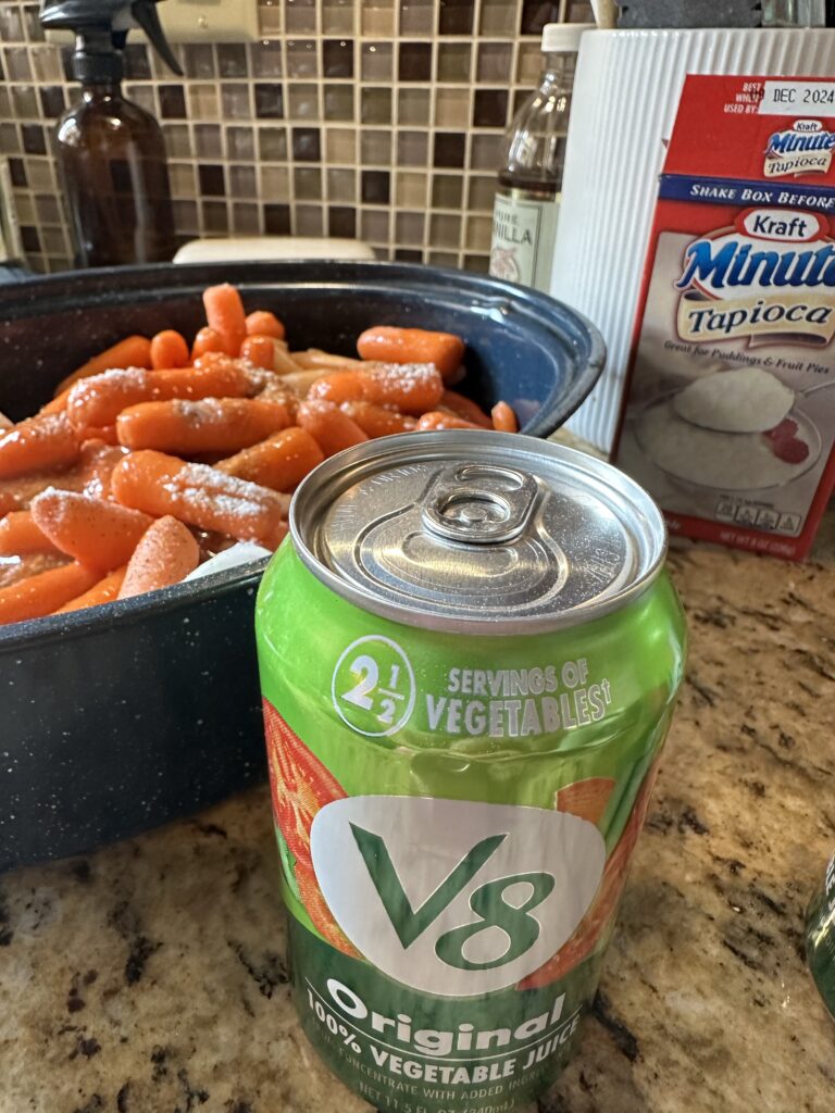 A can of V8 in front of the speckled roaster with the beef stew components