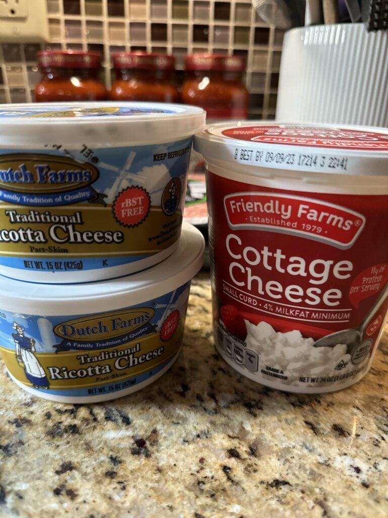 Two containers of ricotta cheese stacked on top of each other and a container of cottage cheese next to them