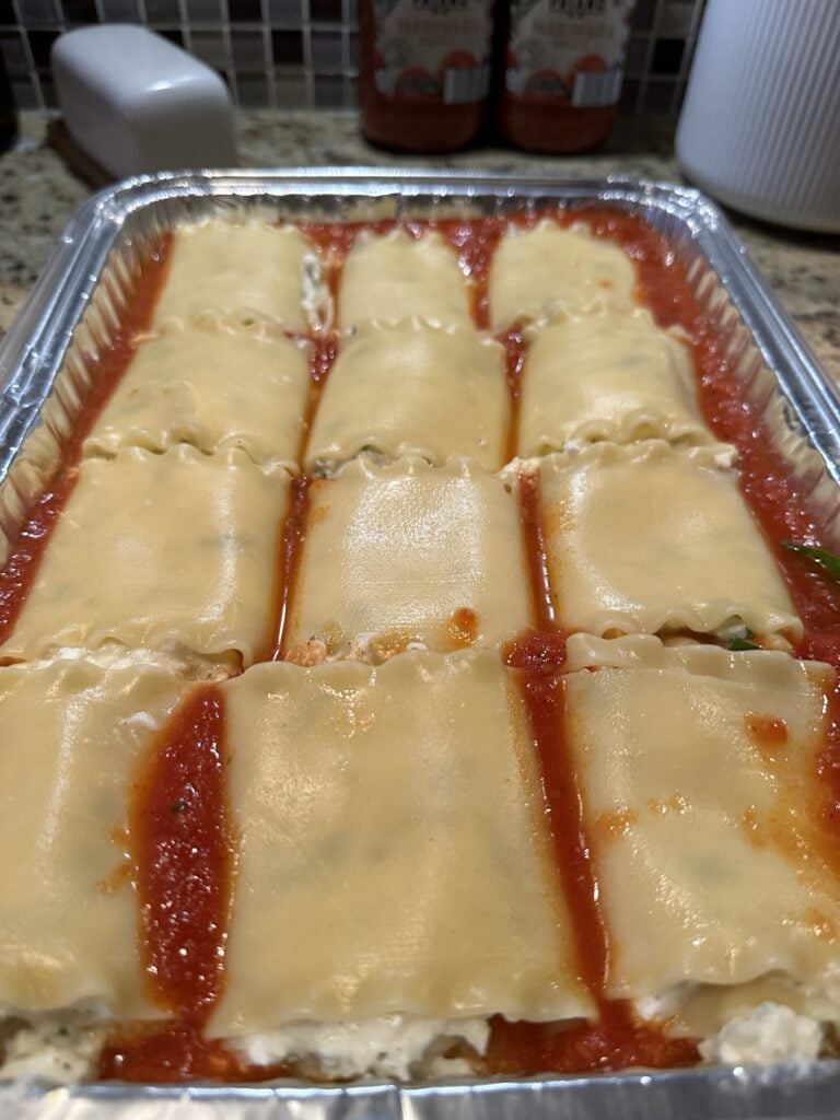 The lasagna noodle rolls arranged in tomato sauce in the baking tin